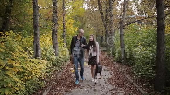 爸爸和女儿一起在秋天公园散步并在照相机上拍照视频的预览图