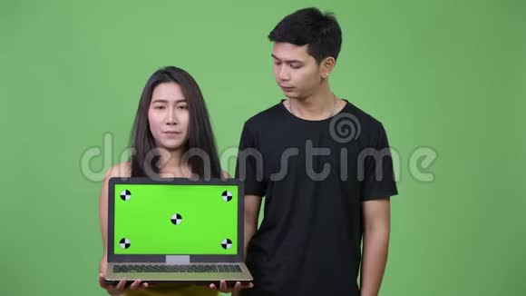 年轻的亚洲夫妇带着笔记本电脑竖起大拇指视频的预览图