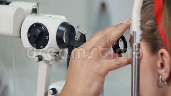 男眼科医生正在用裂隙灯和镜片看女病人的眼睛视频的预览图