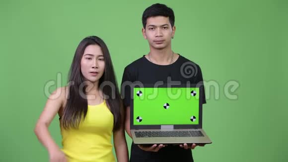 年轻的亚洲夫妇带着笔记本电脑竖起大拇指视频的预览图