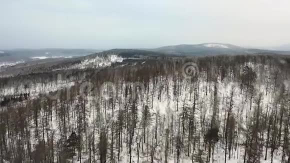 鸟瞰白雪皑皑的森林和山丘多云坏阴多雾天气无人驾驶飞机飞行视频的预览图