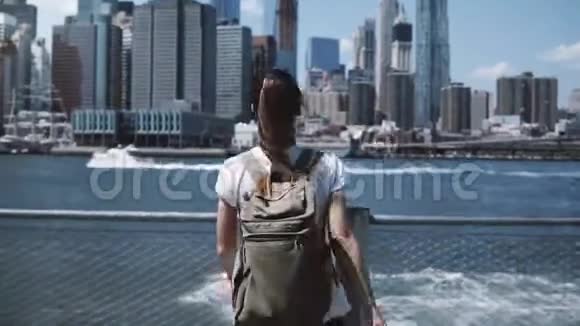 后景的快乐女游客与背包举臂宽开在纽约天际线视图回首相机视频的预览图