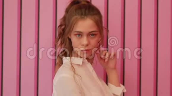 在粉红色墙边摆姿势的女孩视频的预览图