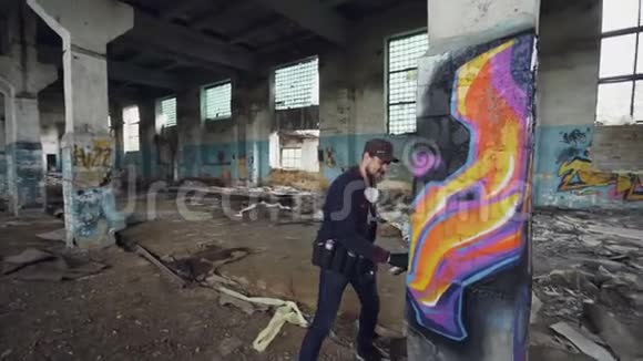 被损坏的废弃建筑的潘射里面有高柱男性涂鸦艺术家在上面画抽象的图像视频的预览图