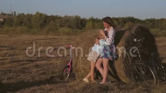 妈妈和女儿在干草堆上玩快乐的一家人在草垛上玩得开心家庭观念视频的预览图
