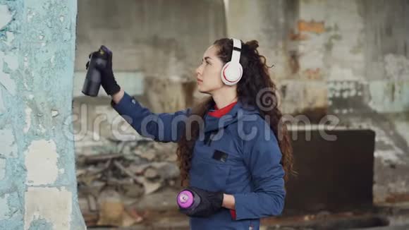 城市街头艺术家戴着耳机听着音乐在老空屋的墙上画画漂亮姑娘视频的预览图