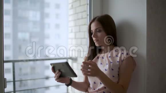 女人在平板电脑里读东西看着窗户视频的预览图