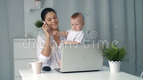 年轻的母亲在家里工作时抱着孩子视频的预览图