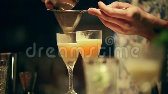 酒保在工作在杯子里混合一杯含酒精的鸡尾酒从筛子中筛出一种成分视频的预览图