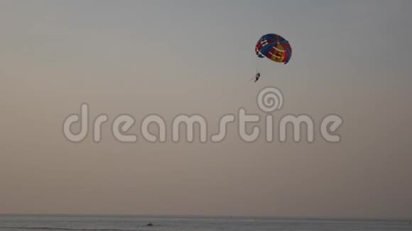 日落时在热带海滩进行降落伞活动平静的海水和带降落伞的海滩娱乐活动拖着一个视频的预览图