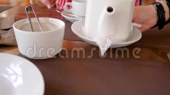 两个人的特写一个服务员在桌子上带来热咖啡和茶服务员把杯子和杯子放在饮料里视频的预览图