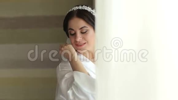 婚礼当天新娘穿着一件缎子睡衣靠近窗户视频的预览图