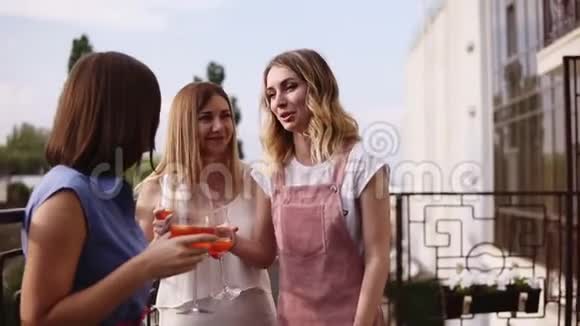 三个现代年轻的女人正在谈论和喝橙色鸡尾酒从酒杯分享故事和欢笑视频的预览图