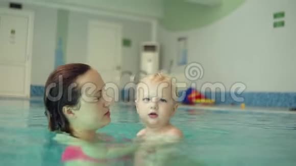 靠近一个年轻的湿漉漉的女人和他的金发小儿子游泳在水面上旋转飞溅祝你快乐视频的预览图