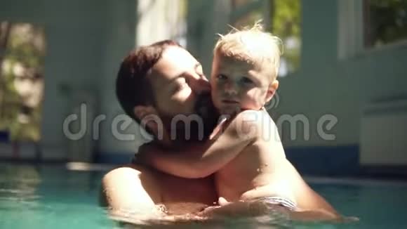 一对父子在游泳池里共度时光的肖像太阳落山了父亲拥抱他视频的预览图