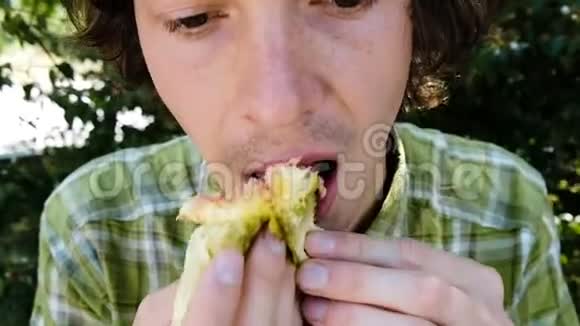 一个男人在一个夏季公园特写镜头中吃一个成熟的无花果的肖像动作缓慢视频的预览图