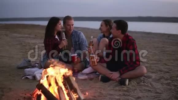 无忧无虑的年轻朋友在一起在太阳落山的时候在海滩边喝着烈性啤酒视频的预览图