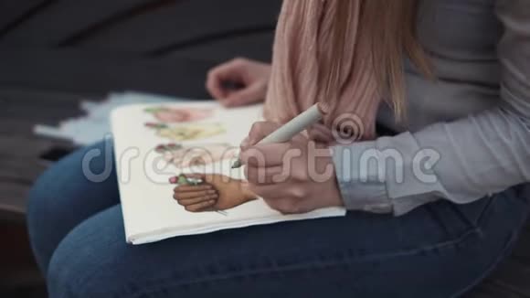 年轻的学生女孩用毛毡笔勾勒出明亮的画面用手特写视频的预览图