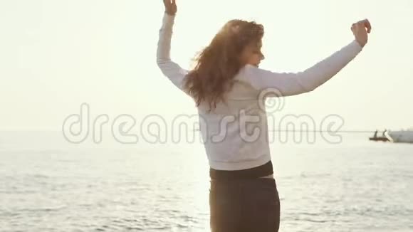 快乐的女人在阳光下在沙滩上旋转视频的预览图