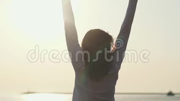 年轻苗条的女人伸出双手站在海上日出前视频的预览图