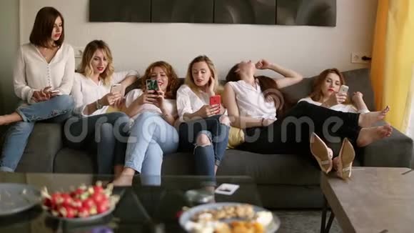 六个漂亮的女孩在沙发上放松女孩们正在调查她们的手机休息一下轩党概念视频的预览图