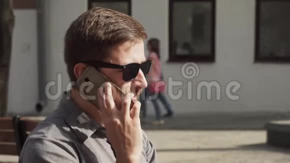 戴墨镜的欧洲商人在城市街头谈论智能手机视频的预览图