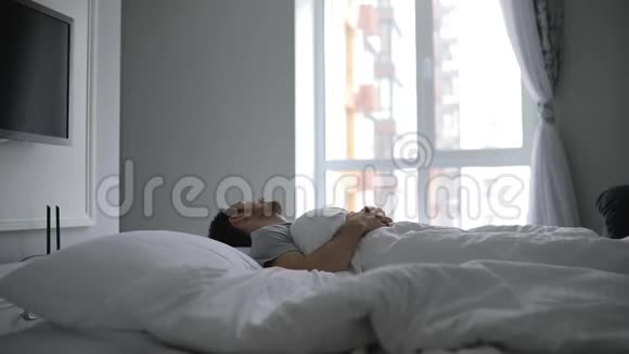清晨醒来的男人躺在床上伸着胳膊视频的预览图