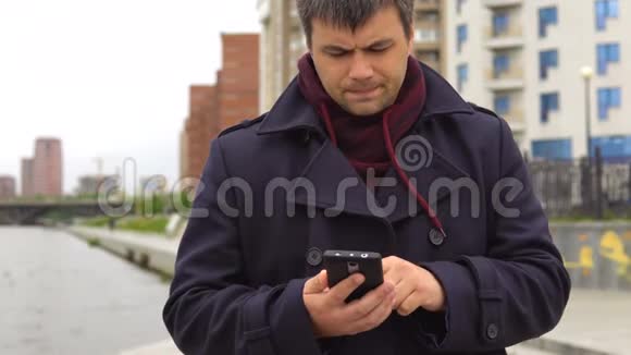 一个男人在城市景观的背景下使用手机视频的预览图