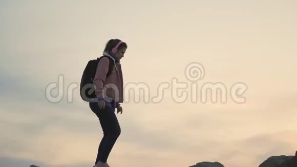 年轻的女旅行者沿着山脊走陡峭的山日落时可以看到美丽的海景视频的预览图