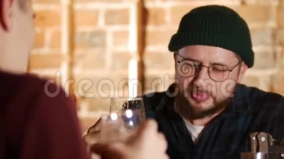 戴眼镜的胡子男在酒吧和他的朋友聊天啤酒关门视频的预览图