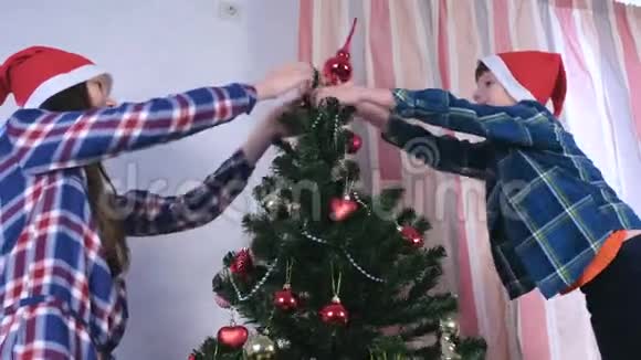 母亲和儿子戴着圣诞帽把尖顶放在圣诞树上视频的预览图