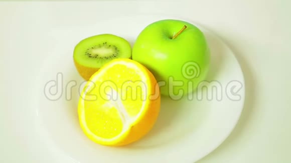 白色盘子里的橙皮猕猴桃和绿皮苹果的两半旋转成一个圆圈视频的预览图