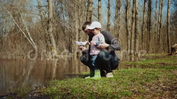 年轻的一家人正在水上开一艘玩具纸船视频的预览图