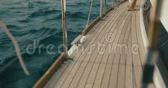 在游艇上放松光着脚的女人小心翼翼地走在湖上某个地方的游艇上视频的预览图