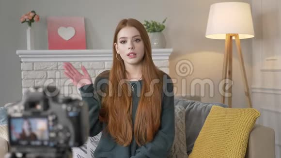 年轻的红色悲伤的女孩博主在镜头前说话用手做手势背景中的孤独60英尺视频的预览图