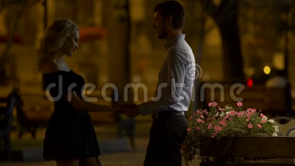 男人牵着女朋友的手拥抱她晚上在城市公园约会爱视频的预览图