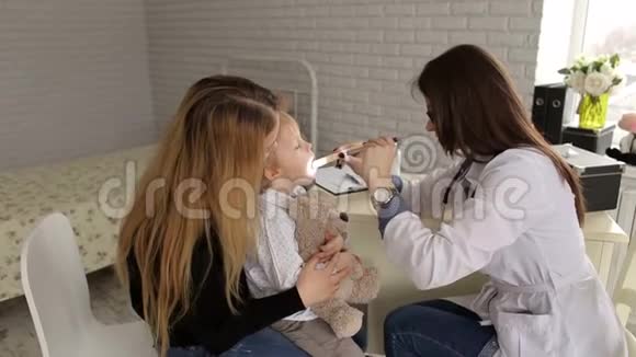 医生用手电筒和铲子检查小孩的喉咙视频的预览图
