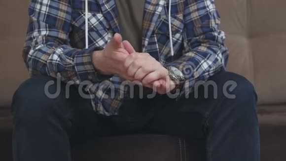 一个人坐在沙发上用手打手势把它们弄皱互相摩擦视频的预览图
