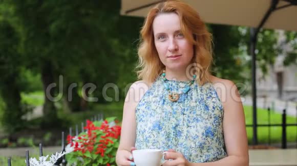 一个夏天咖啡馆里的女人正在喝茶特写站着女人穿着裙子站在公园的背景上视频的预览图