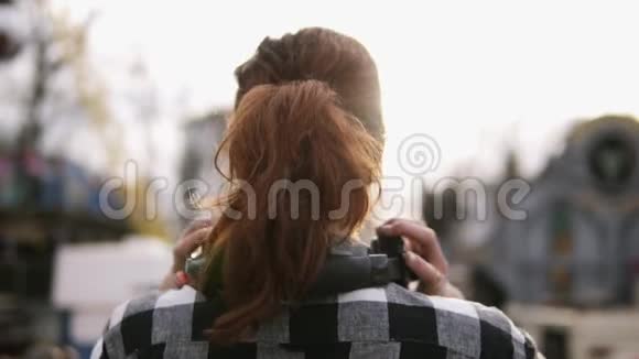 背面的镜头是一个女孩有一条棕色头发的尾巴站着一件格子衬衫靠在阳光下穿上视频的预览图