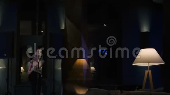 有才华的年轻女子在夜间在舒适的房间用麦克风演唱歌曲在红色史诗4KUHD相机上拍摄视频的预览图