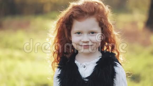 秋天公园里可爱的红头发小女孩的肖像慢动作秋天公园小女孩正微笑着看着视频的预览图