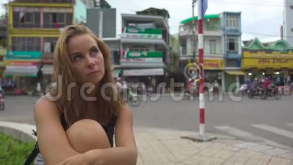 肖像沉思的女人坐在城市街道和汽车交通背景面对一个体贴又悲伤的女孩视频的预览图