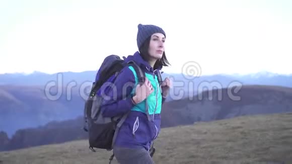 女游客背着背包在山上的背景上视频的预览图