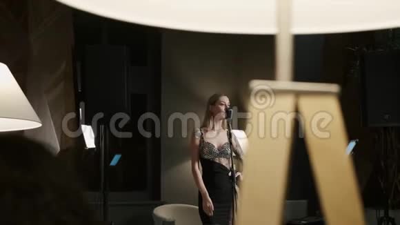 有才华的年轻女子在夜间在舒适的房间用麦克风演唱歌曲在红色史诗4KUHD相机上拍摄视频的预览图