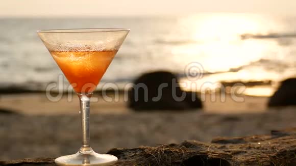 4K日落时分海滩上有水滴的鸡尾酒杯有金色的波浪反射视频的预览图