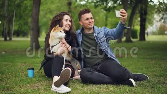 帅哥正在和抱着家狗的女朋友自拍男的在亲女孩子然后看着视频的预览图