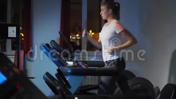年轻漂亮的女孩在健身中心跑步机上跑步视频的预览图