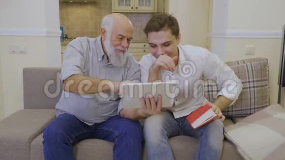 现代祖父在互联网上用数字平板电脑向孙子展示视频视频的预览图