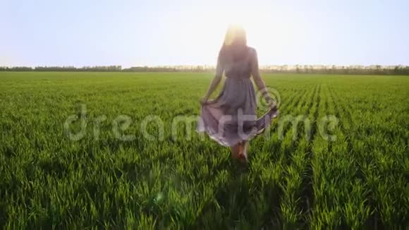 穿着粉色衣服的女人光着脚走在绿色的田野上视频的预览图
